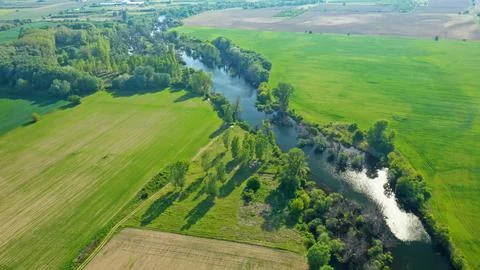 High view over river and trees along farm field Stock Photos