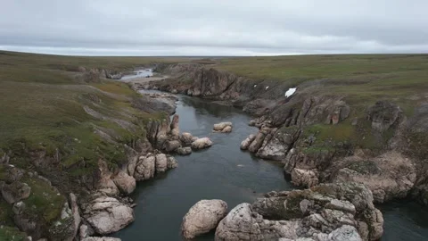 High View Of Rocky Crack Filled With Icy Patches And Gentle Flowing Waters in Stock Footage 339695724