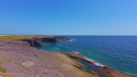 High view of rocky headland extending into blue ocean water Stock Footage 340451600