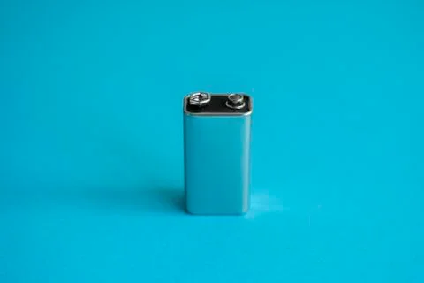 High voltage battery on a blue background. Silver Volt battery. 9V Advanced Stock Photos