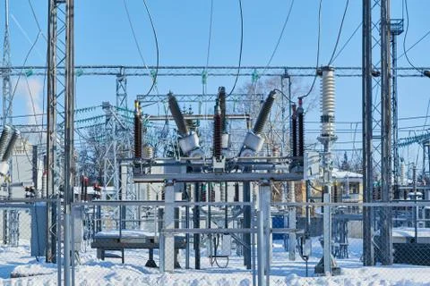 High-voltage circuit breakers at electrical substations connected with wires. Stock Photos