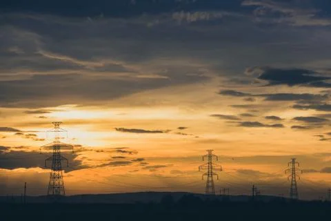 High voltage electic pylon line on party cloud sunset Stock Photos