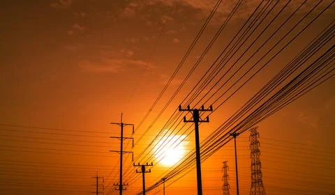 High voltage electric pole and transmission lines at sunset time with orang.. Stock Photos