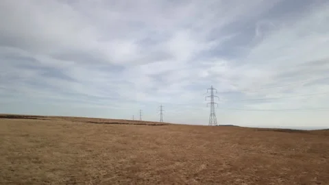 High voltage electric pylons on a dry field - Peak District, United Kingdom Stock Footage