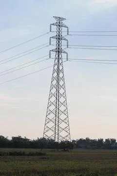 High-voltage electric tower model standing in the middle of a rice field Stock Photos