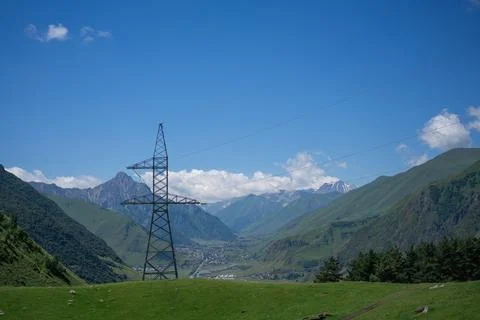High Voltage Electric Tower Pole on Blue Sky and Mountains Background with .. Stock Photos