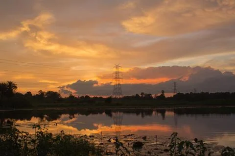 High voltage electric tower with reflection in a pond at sunset Stock Photos
