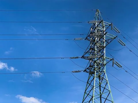 High voltage electrical network on blue the sky backdrop. Stock Photos