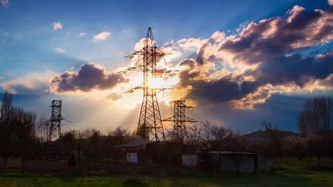 High voltage electrical pole structure on background dramatic sunset with fluffy Stock Photos