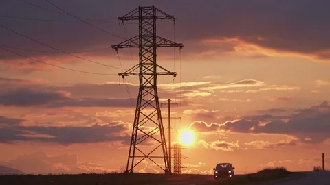 High-voltage electrical support, an amazing orange sunset and the car goes on th Stock Footage 105534044