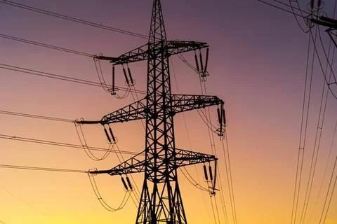 High voltage electrical tower against colorful sunset sky Stock Photos