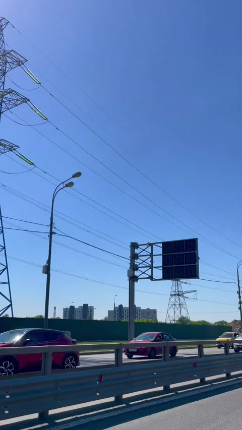 High voltage electrical tower on highway with driving cars. Power transmission Stock Footage 339432153