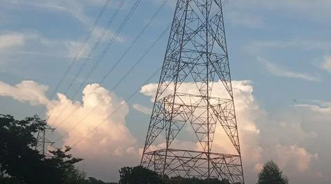 High-voltage electrical transmission tower against a blue sky with clouds Stock Photos