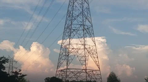 High-voltage electrical transmission tower against a blue sky with clouds Stock Photos