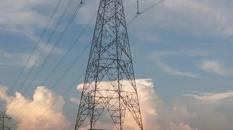 High-voltage electrical transmission tower against a blue sky with clouds Stock Photos
