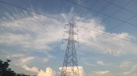 High-voltage electrical transmission tower against a blue sky with clouds Stock Photos