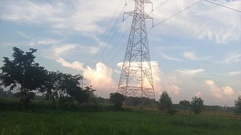 High-voltage electrical transmission tower against a blue sky with clouds Stock Photos