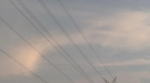 High-voltage electrical transmission tower against a blue sky with clouds Stock Photos