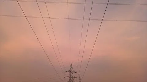 High-voltage electrical transmission tower during twilight or sunset Stock Photos