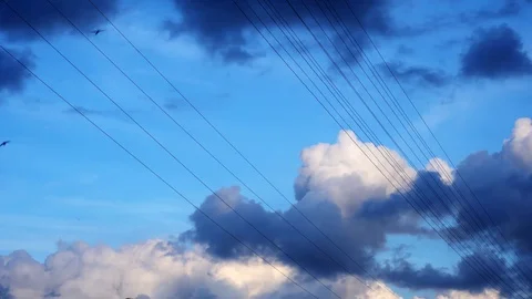 High-voltage electrical wires against a blue sky with floating clouds and birds. Video stock 108673205