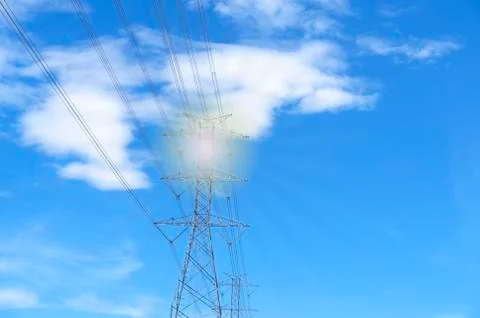 High voltage of electricity pole with cable on clouds blue sky and sun light. Stock Photos