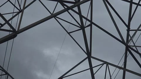 A high-voltage electricity pylon lattice frames a close-up view passing down to 库存影片 337476823
