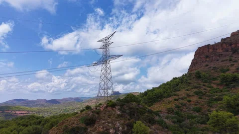 High voltage electricity pylon standing on a green hillside in a mountainous Stockbeeldmateriaal 345103909