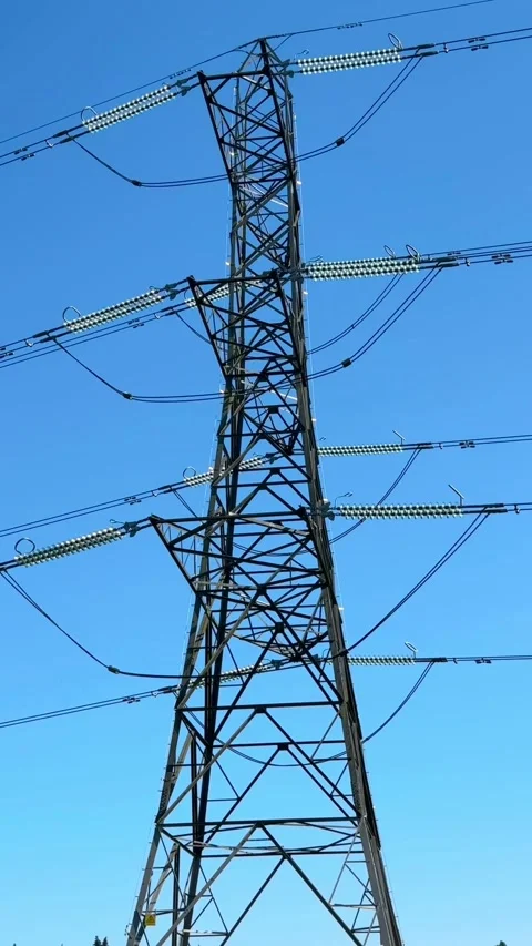 A high-voltage electricity pylon standing in a green agricultural field Stock Footage 346411161