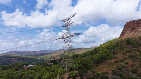 High voltage electricity pylon standing among green hills and rocky mountains Stock Footage 346940583