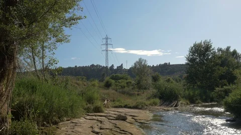High voltage field tower electricity modern river stream water wide llobre Stock Footage 113112897