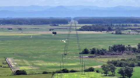 High voltage grid and wind turbines over green fields, sideways drone parallax Stock Footage 328573978