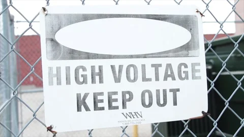 High voltage keep out rectangle white and black sign on silver diamond fence Stock Footage 249752240