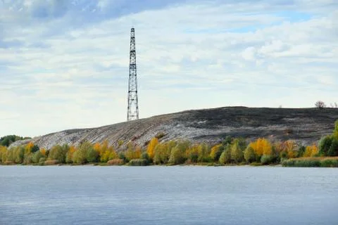 High voltage line and electricity pylon on coastline of river. Stock Photos