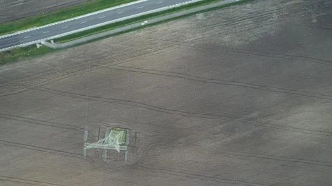 High voltage line - pole - single lane road and passing cars - plowed field Stock Footage 271298110