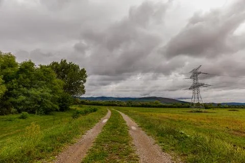 High voltage overhead power line. Green meadow with a cloudy stormy sky Stock Photos