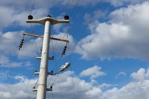 High-voltage pole with insulators and wires against blue sky. Stock Photos