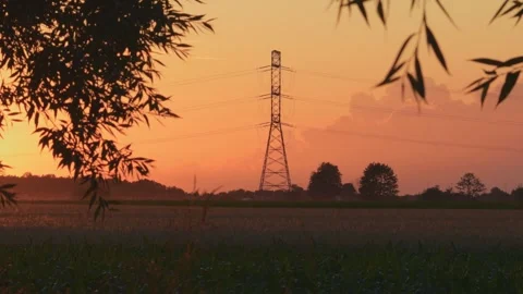 High voltage pole next to road at sunset, view from agricultural field. Stock Footage 245004191