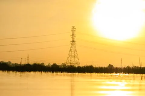 High voltage post on landscape view at morning with Sky yellow and river back Stock Photos