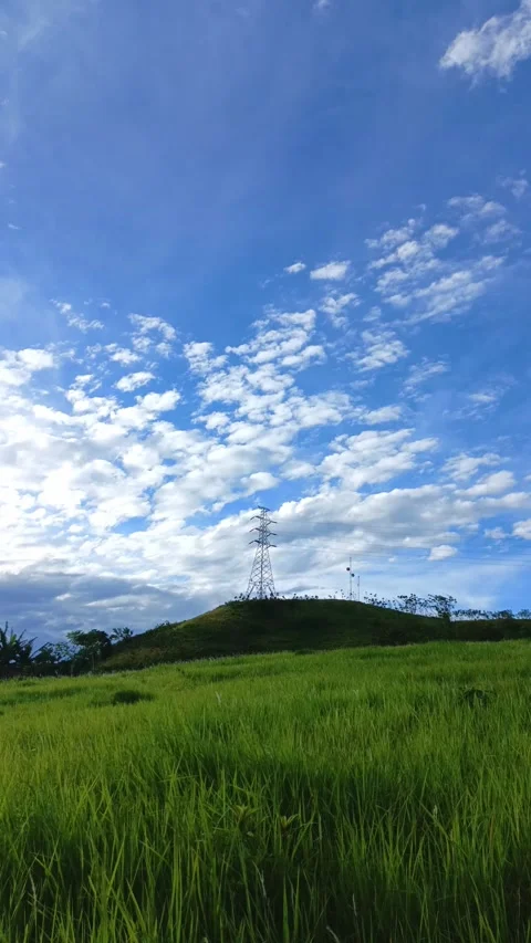 High voltage power line in the blue sky with cloud and green hill Stock Footage 297483791