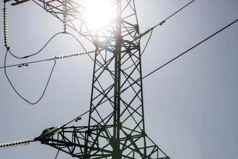 High voltage power line tower in the background of a bright sun Foto stock