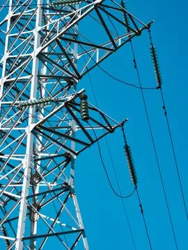 High voltage power line tower against a clear blue sky with metal structure and Stock Photos