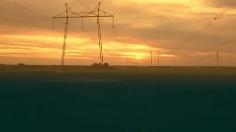 High-voltage power lines against the backdrop of the setting sun on the plain Stock Footage 154658769