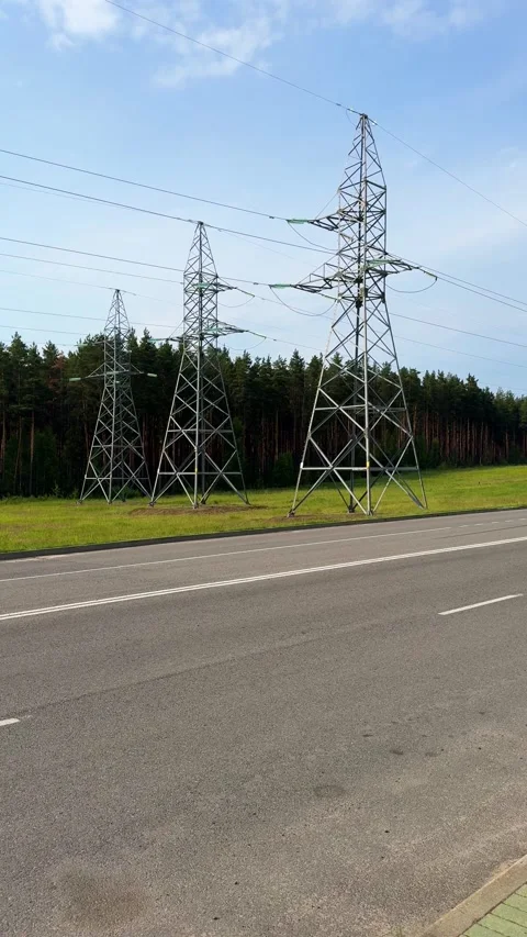 High voltage power lines and transmission line pylons along the highway Stock Footage 336796281