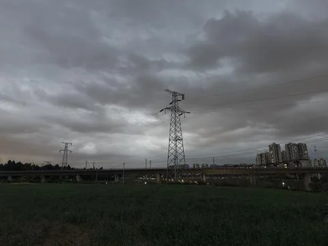 High Voltage Power Lines and City Skyline under Dark Clouds Stock Photos