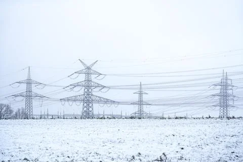 High voltage power lines and transmission towers in winter snow field Stock-Fotos