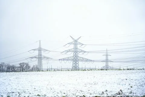 High voltage power lines and transmission towers in winter snow field Stock-Fotos