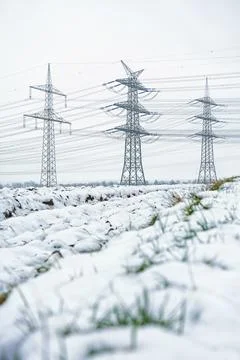 High voltage power lines and transmission towers in winter snow field Stock-Fotos