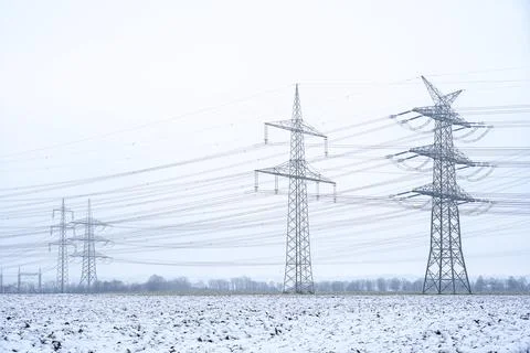 High voltage power lines and transmission towers in winter snow field Stock-Fotos