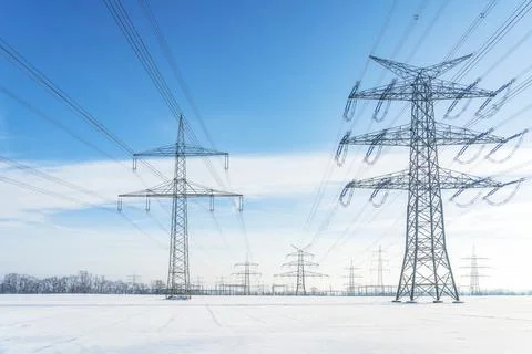 High voltage power lines and transmission towers in deep winter snow field Stock-Fotos