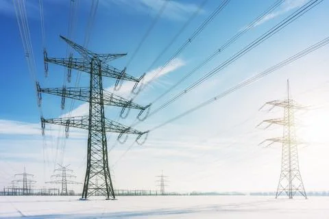 High voltage power lines and transmission towers in deep winter snow field Stock-Fotos